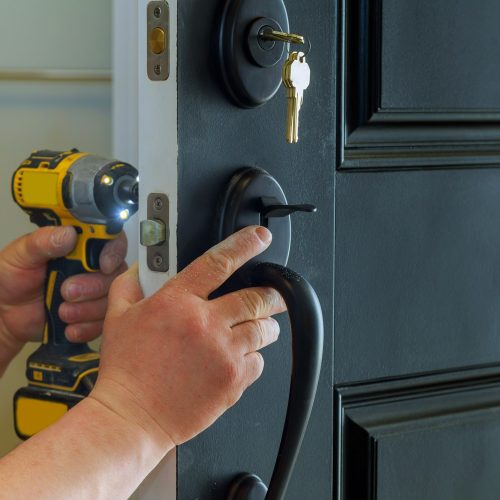 Closeup of a professional locksmith installing a new lock on a house exterior door with the inside