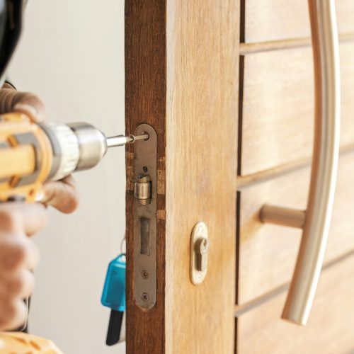 Locksmith hands, maintenance and handyman with drill, home renovation and fixing, change door locks